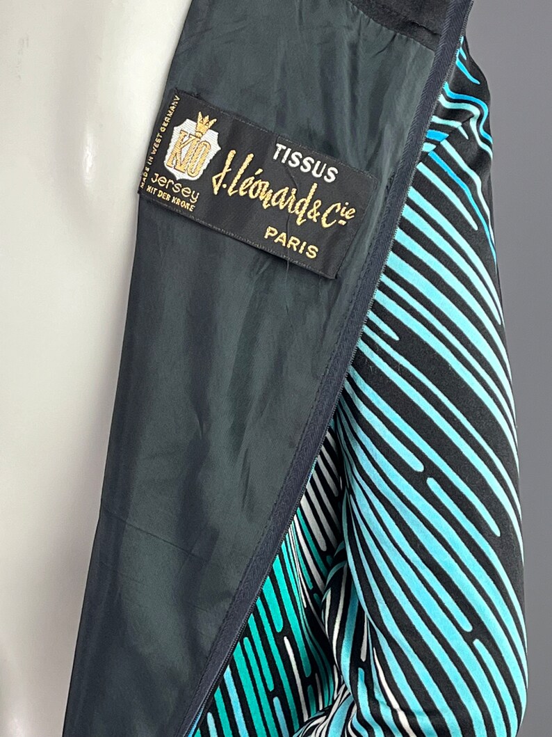 Peut inclure: Une veste ray&eacute;e noire et bleue avec une &eacute;tiquette indiquant "Tissus J. Leonard & Cie Paris" et "Jersey mit der Krone Made in West Germany".