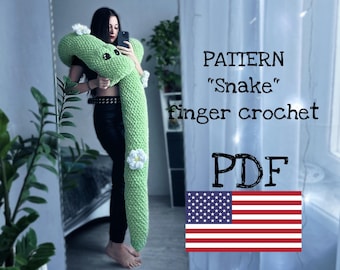 May include: A crochet pattern for a green snake, with white flowers, titled "PATTERN "Snake" finger crochet PDF". The pattern is available as a digital download.