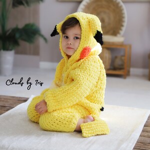 May include: A yellow crocheted Pikachu costume for a child. The costume features a hood with black ears and a red and orange cheek design. The costume is made of soft, chunky yarn.