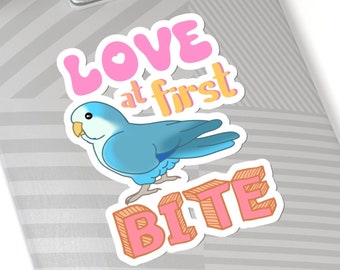 May include: A sticker with a blue and white parakeet and the text "Love at first bite" in pink and orange letters.