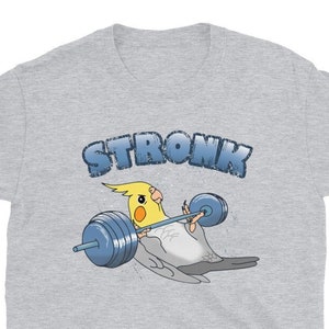 Puede incluir: Una camiseta gris con un cacatúa ninfa amarillo y blanco levantando pesas. El texto "STRONK" está por encima del pájaro.