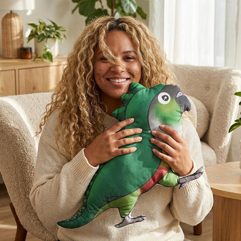 Pu&ograve; includere: Un cuscino di peluche a forma di pappagallo verde con un occhio bianco, becco grigio e dettagli rossi. Il cuscino &egrave; tenuto da una persona che indossa un maglione color crema. Articolo decorativo.