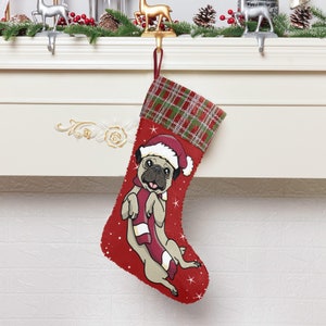 May include: Red and green plaid Christmas stocking with a white background featuring a cartoon pug wearing a Santa hat and a red scarf. The stocking is hanging from a hook.