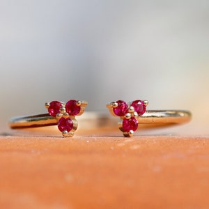May include: A gold ring with three ruby stones set in a triangular shape.