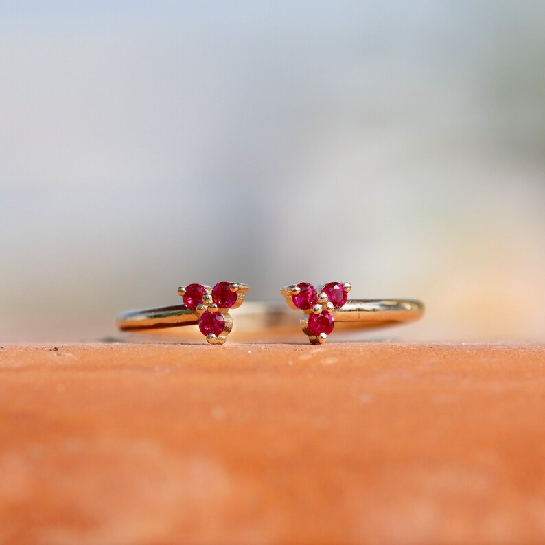 May include: A gold ring with three ruby stones set in a triangular shape.