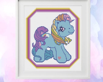 Op de afbeelding: Borduurpatroon voor Rainbow Dash van My Little Pony. Het patroon is 7,5 inch bij 8,4 inch en gebruikt 13 DMC-kleuren. Het patroon is ingelijst en toont een blauw pony met een regenboogmanen en staart.