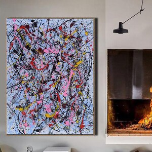 Puede incluir: Pintura abstracta con salpicaduras de pintura negra, blanca, rosa, amarilla y roja sobre un fondo azul claro. La pintura est&aacute; colgada en una pared en una habitaci&oacute;n con una chimenea y suelos de madera.