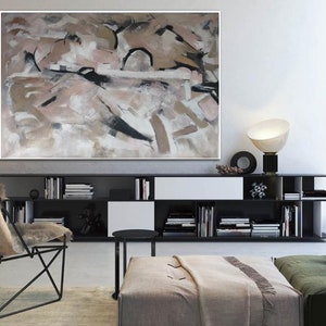 May include: Abstract painting in shades of brown, beige, and white with black accents. The painting is displayed on a wall above a black bookshelf with books and decorative objects.