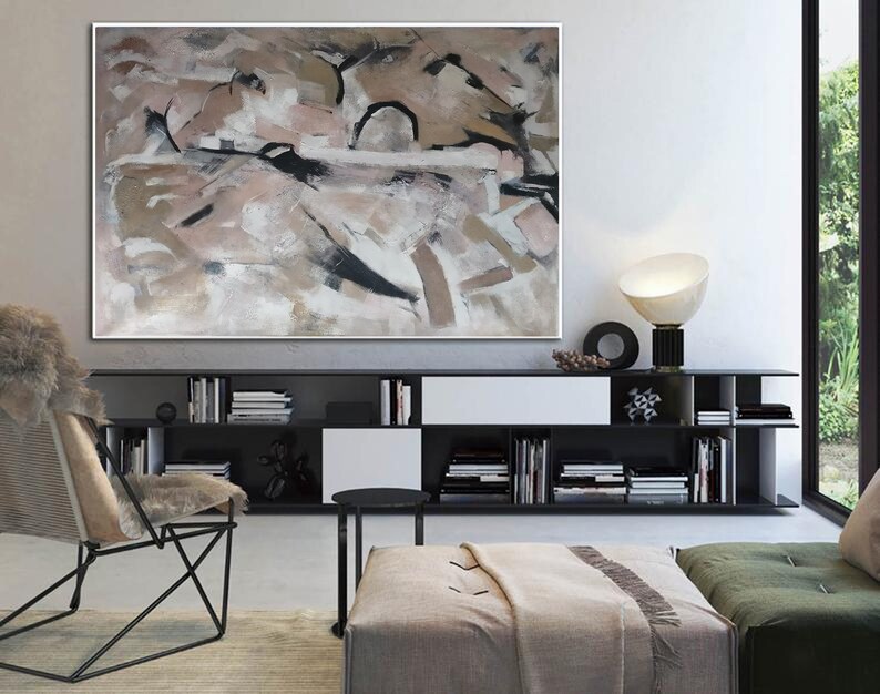 May include: Abstract painting in shades of brown, beige, and white with black accents. The painting is displayed on a wall above a black bookshelf with books and decorative objects.