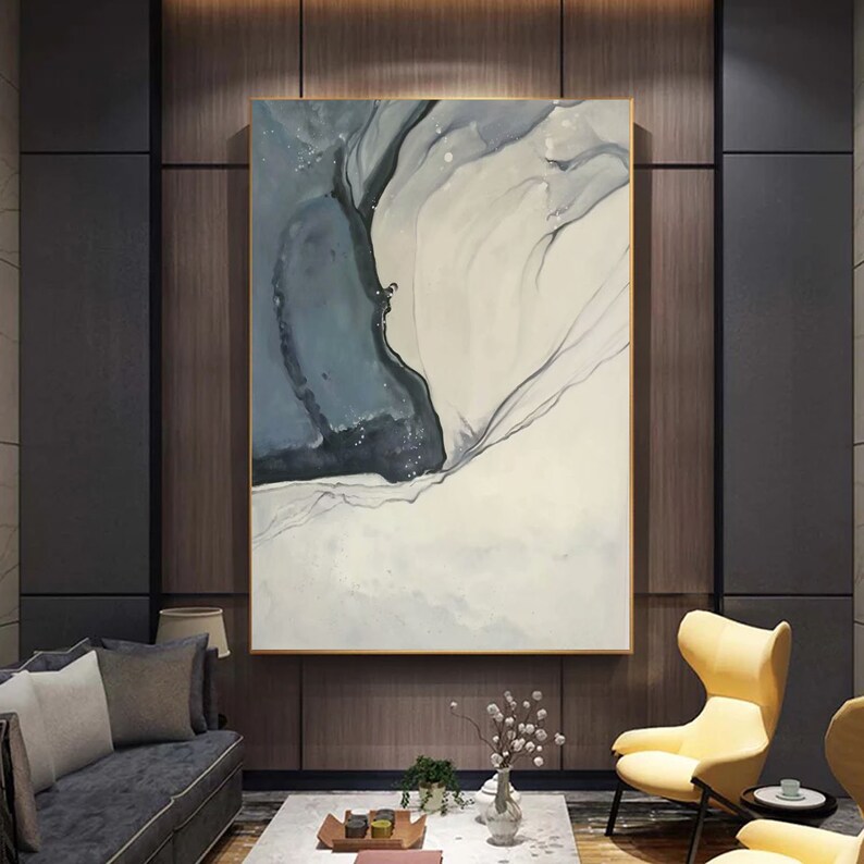 May include: Abstract painting with a white background and a blue and black swirl in the center. The painting is framed in a gold frame.