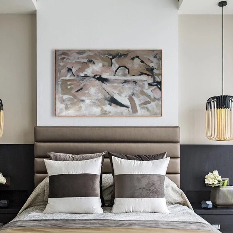 May include: A bedroom with a brown leather headboard and two white and brown striped pillows. A large abstract painting in shades of brown, pink, and black hangs above the headboard. A wooden lamp with a black shade hangs from the ceiling.