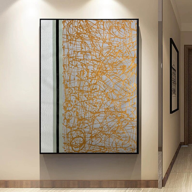 K&ouml;nnte beinhalten: Abstrakter Kunstdruck mit wei&szlig;em Hintergrund und goldenen Linien. Der Druck ist in einem schwarzen Rahmen gerahmt.
