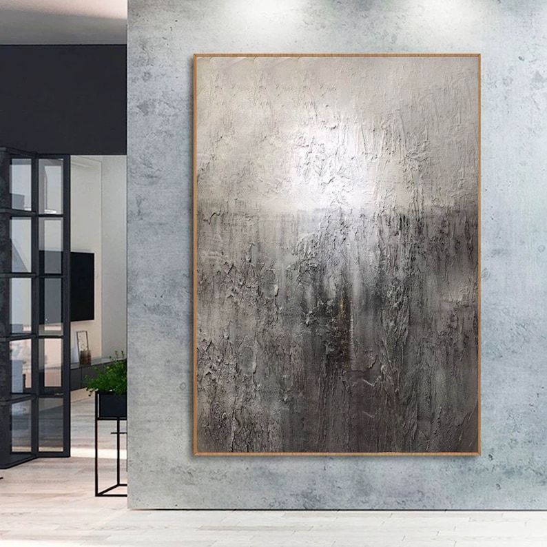 May include: Abstract painting with a textured, gray and white color scheme. The painting is framed in a thin, wooden frame.