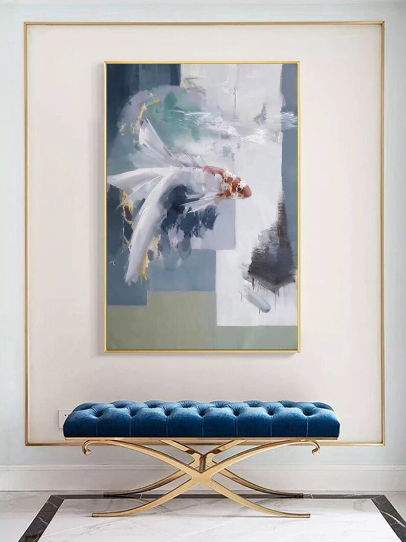 Puede incluir: Un banco tapizado en terciopelo azul con estructura de metal dorado. El banco est&aacute; delante de una pared blanca con una pintura abstracta enmarcada de un pez blanco con detalles dorados y rojos.