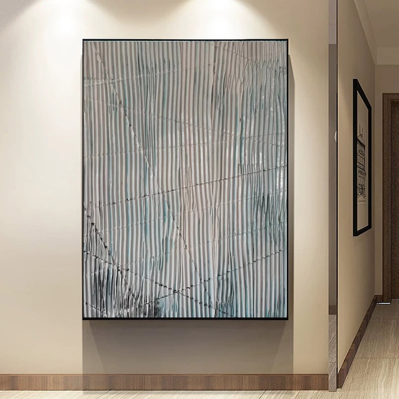 May include: Abstract art print with a white and blue striped pattern. The stripes are wavy and create a sense of movement. The print is framed in a black frame.
