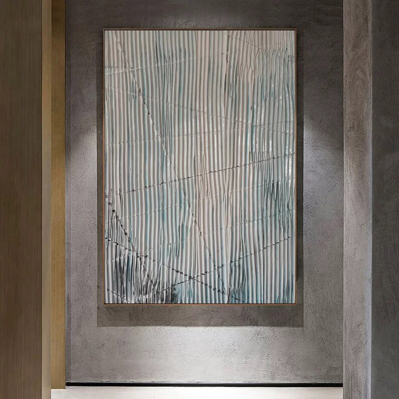 May include: Abstract art painting with a white and blue striped pattern. The painting is framed and hanging on a gray wall.