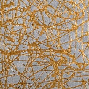 K&ouml;nnte beinhalten: Abstrakte Malerei mit wei&szlig;em Hintergrund und goldenen Farbspritzern und Linien.