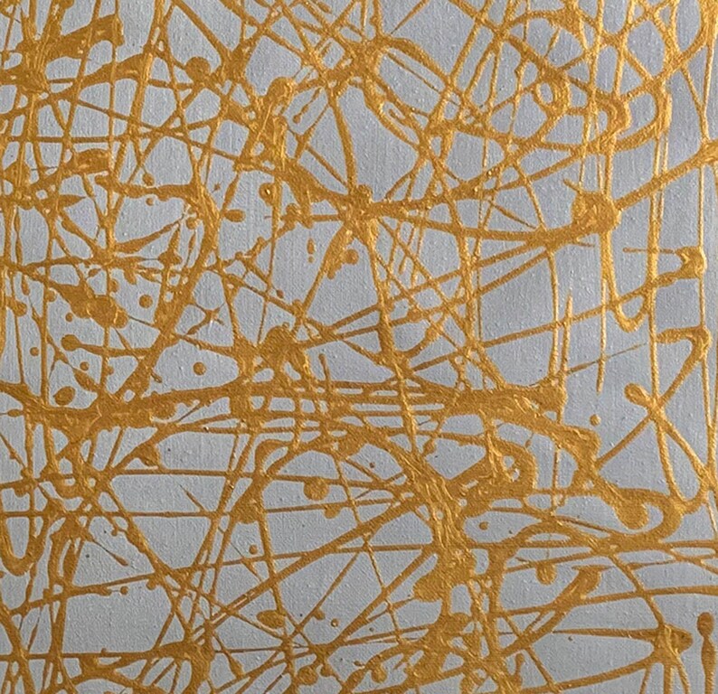 K&ouml;nnte beinhalten: Abstrakte Malerei mit wei&szlig;em Hintergrund und goldenen Farbspritzern und Linien.