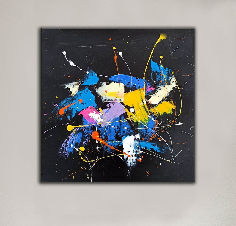 May include: Abstract painting with a black background and colorful splashes of blue, yellow, pink, white, and orange paint. The paint is splattered and dripped across the canvas, creating a dynamic and energetic composition.