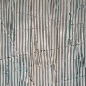May include: A close-up of a textured wall with vertical lines in shades of white and light blue. The lines are arranged in a pattern that creates a sense of depth and dimension.