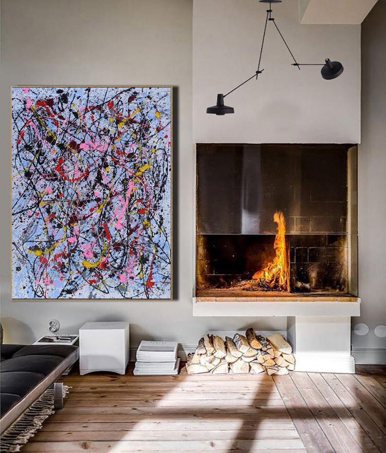 Puede incluir: Pintura abstracta con salpicaduras de pintura negra, blanca, rosa, amarilla y roja sobre un fondo azul claro. La pintura est&aacute; colgada en una pared en una habitaci&oacute;n con una chimenea y suelos de madera.