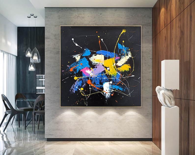 Abstract painting with splashes of blue, yellow, pink, and orange paint on a black background.