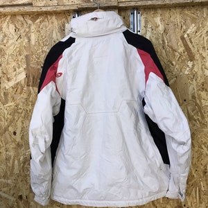 Puede incluir: Chaqueta de invierno blanca y negra con detalles en rojo. La chaqueta est&aacute; colgada de un gancho met&aacute;lico. Tiene un cuello alto y cierre de cremallera. Fabricada con material resistente al agua.