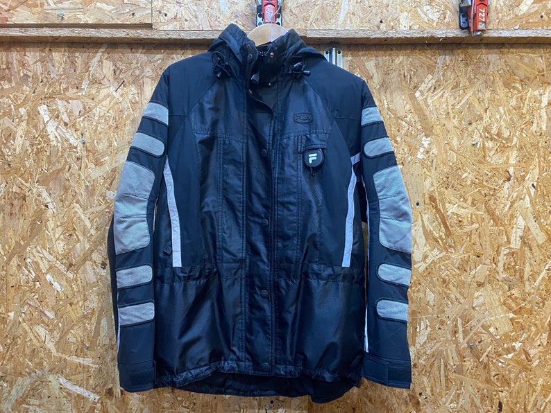 May include: Black and gray winter jacket with a hood. The jacket features gray padded sections on the sleeves and a small logo on the chest. The jacket has a button and zipper closure.