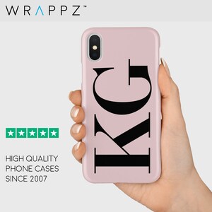 May include: A pink iPhone case with a black monogram design featuring the letters "KG".