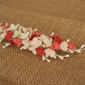 以下が含まれることがあります： 白、ピンク、赤のフェルトの花がついた、繊細な花のヘアコーム。どんなヘアスタイルにもエレガントさを添えるのに最適です。