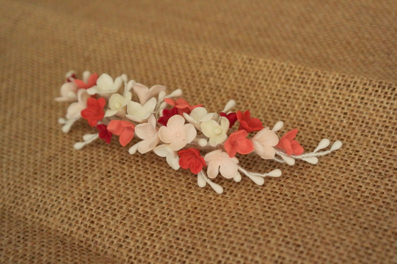 以下が含まれることがあります： 白、ピンク、赤のフェルトの花がついた、繊細な花のヘアコーム。どんなヘアスタイルにもエレガントさを添えるのに最適です。