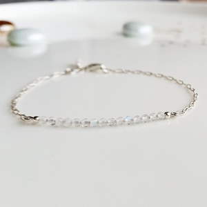 May include: A delicate silver chain bracelet with a row of clear moonstone beads.