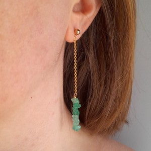 May include: Gold chain earrings with a cluster of green gemstone chips dangling from the bottom.