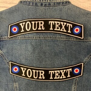 May include: Two black and white embroidered patches with a red, white and blue target design on each end. The patches are curved and say "YOUR TEXT" in white letters.