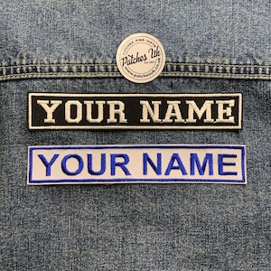 May include: Two rectangular embroidered patches with the text "YOUR NAME" in white and blue. The top patch has a black background, the bottom a white one. A circular patch with text is at the top. Patches are displayed on denim.
