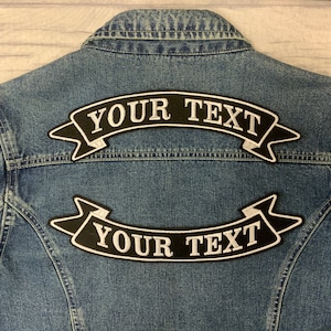 May include: Two black fabric patches with white stitching in the shape of a banner. The banner reads "YOUR TEXT".