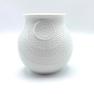 Puede incluir: Jarrón de cerámica blanca con un diseño en relieve intrincado de círculos y puntos superpuestos.