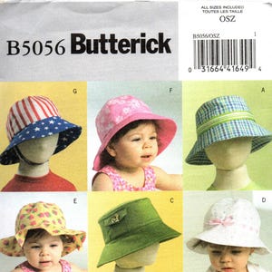 May include: A Butterick B5056 sewing pattern envelope featuring illustrations of six different bucket hats. The designs include a red and white striped hat with a blue star-patterned brim, a pink floral hat, a blue plaid hat, a yellow strawberry print hat, a solid green hat, and a white hat with a pink ribbon.
