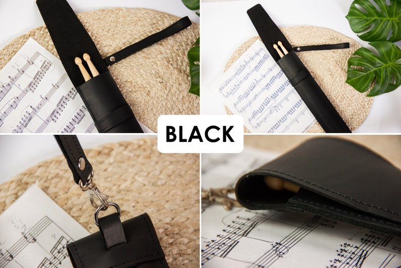 May include: Black leather drumstick holder with a strap and a snap closure. The holder is lying on a sheet of music.