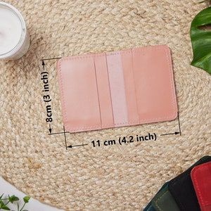 May include: A pink leather card holder with three slots for cards. The card holder measures 4.2 inches by 3 inches.
