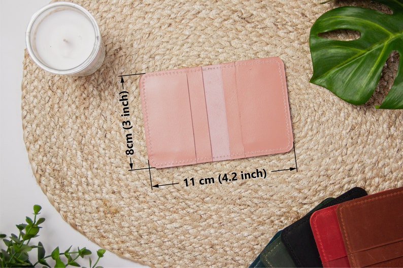 May include: A pink leather card holder with three slots for cards. The card holder measures 4.2 inches by 3 inches.