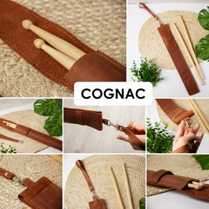 May include: A brown leather drumstick holder with a strap and a silver buckle. The holder is shown with two wooden drumsticks inside. The holder is labelled "COGNAC".