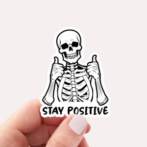Sticker graphic of skeleton giving two thumbs up with the words stay positive
