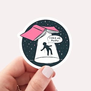 May include: A pink book with the text "Take Me Away" in a speech bubble, floating above a person in a dark blue space with stars. The sticker is 2.5 inches by 2.5 inches.