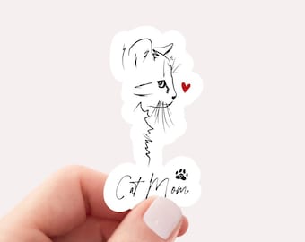 May include: A white sticker with a black line drawing of a cat's head with a red heart. The text "Cat Mom" is written below the cat with a black paw print.