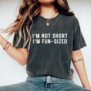 May include: A dark grey t-shirt with the text "I'm not short I'm fun-sized" printed in white.
