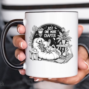 Black accent coffee mug with skeleton reading while lounging in a boho style room with the words Just One More Chapter