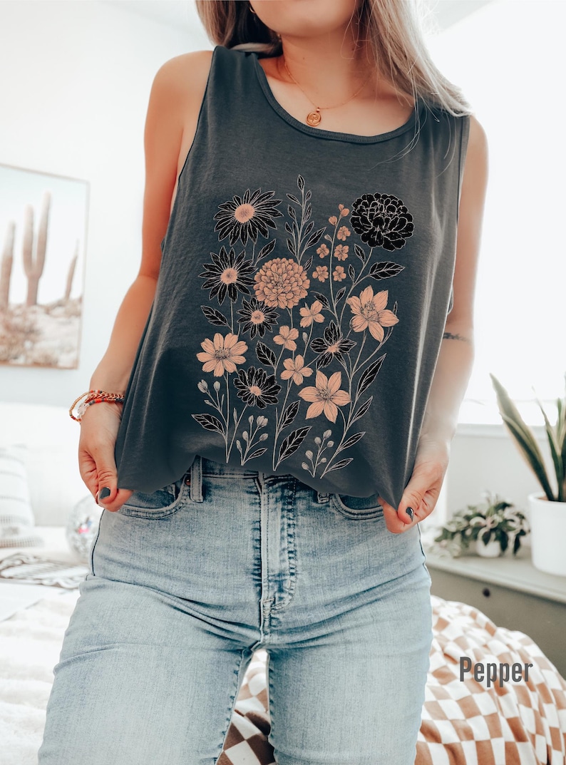 K&ouml;nnte beinhalten: Ein dunkelgraues Tanktop mit einem Blumendesign mit schwarzen und pfirsichfarbenen Blumen. Das Tanktop wird mit hellblauen Jeans kombiniert. Das Wort "Pepper" ist unten rechts im Bild aufgedruckt.