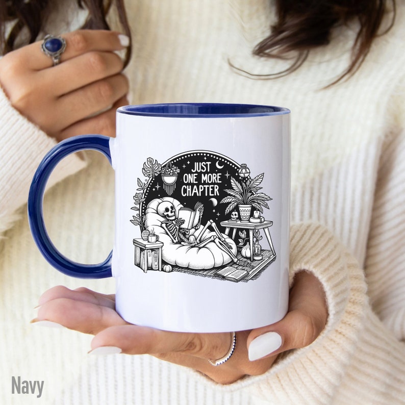 Navy accent coffee mug with skeleton reading while lounging in a boho style room with the words Just One More Chapter