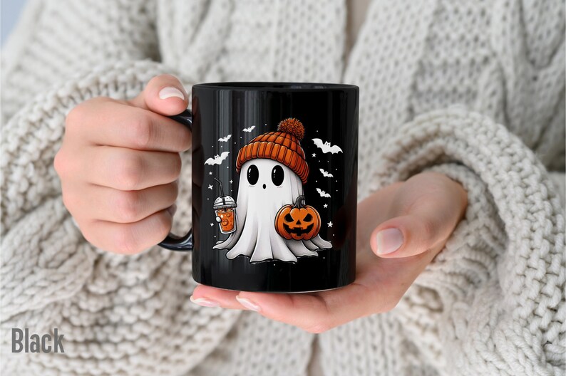 May include: Black ceramic mug with a white ghost wearing an orange and brown beanie holding a pumpkin and a cup of orange liquid. The ghost is surrounded by bats and stars.